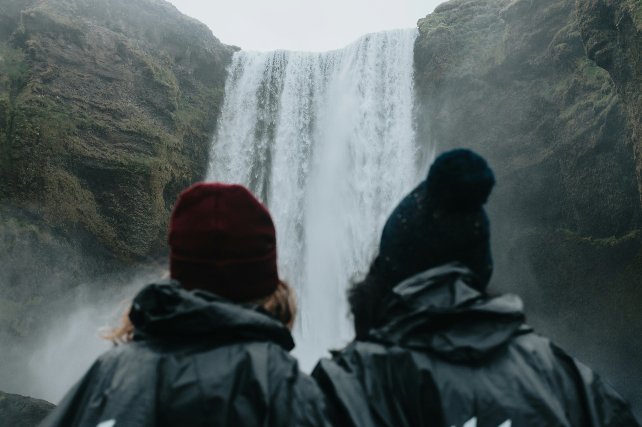 A couple watching Skógafoss Waterfall together in Iceland.