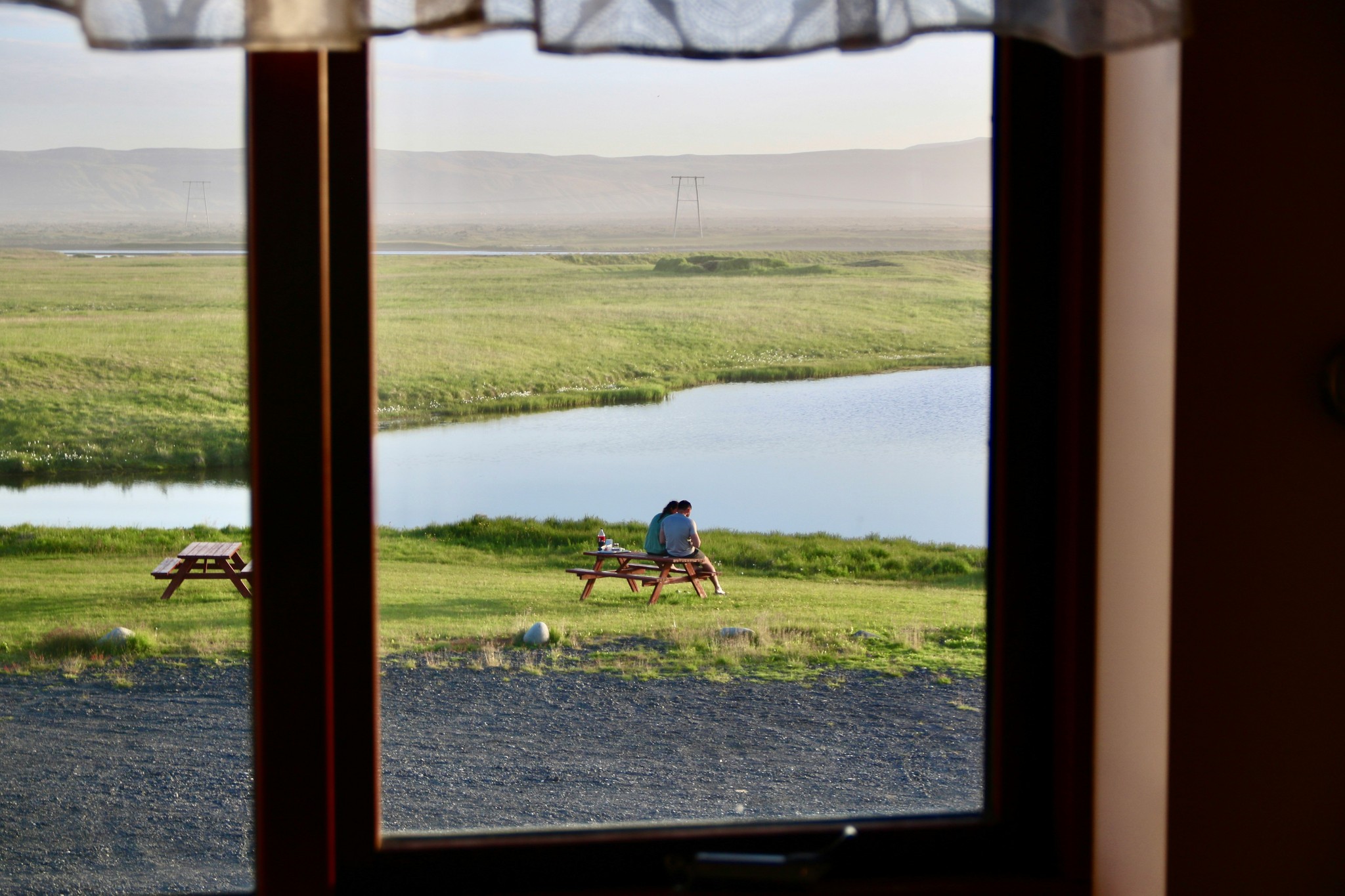 A couple sitting on a wooden bench overlooking a lake in Iceland.