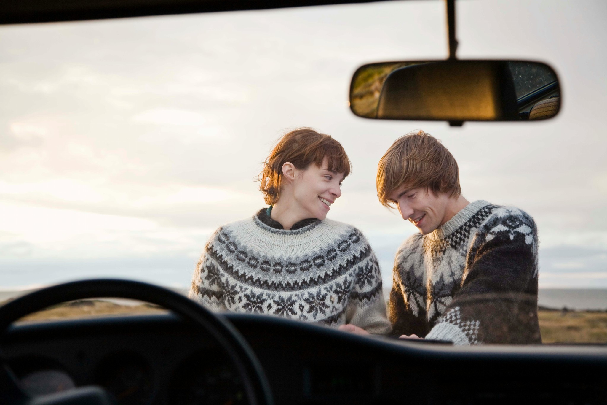 Couple wearing lopapeysa sweaters on an Icelandic road trip.
