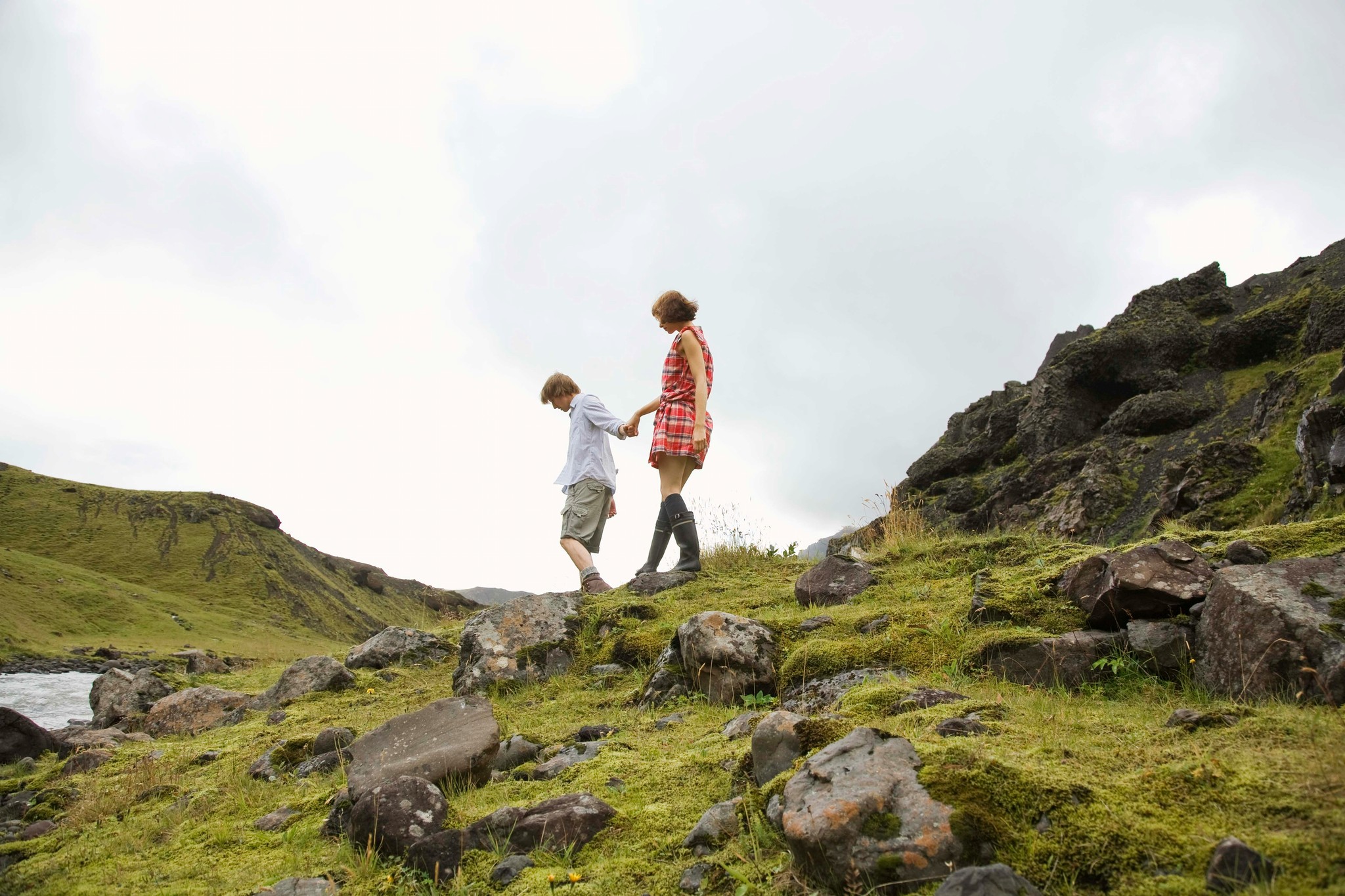A couple walking across a mossy volcanic landscape in Iceland.