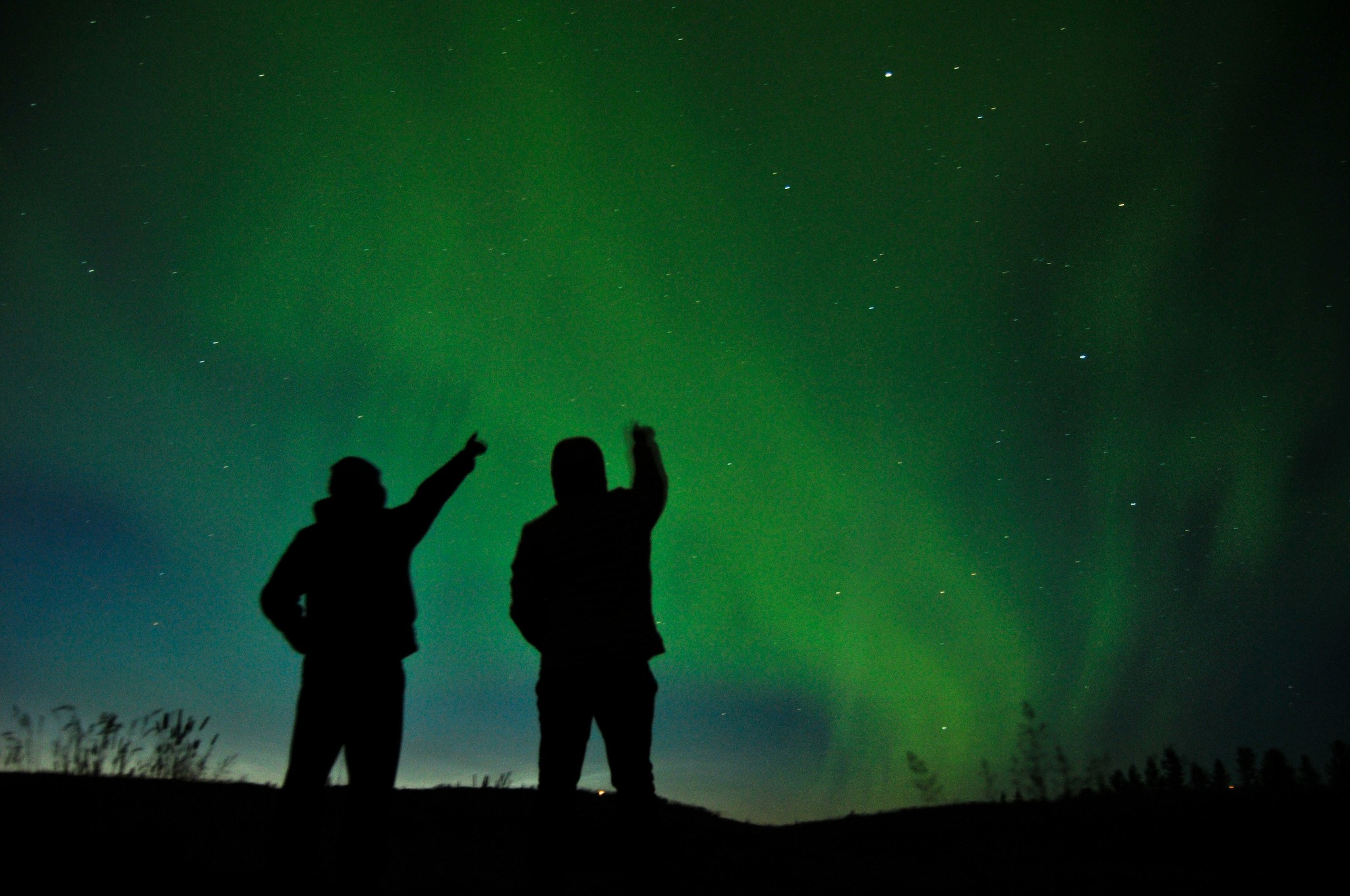 Couple watching and pointing at the Northern Lights in Iceland.