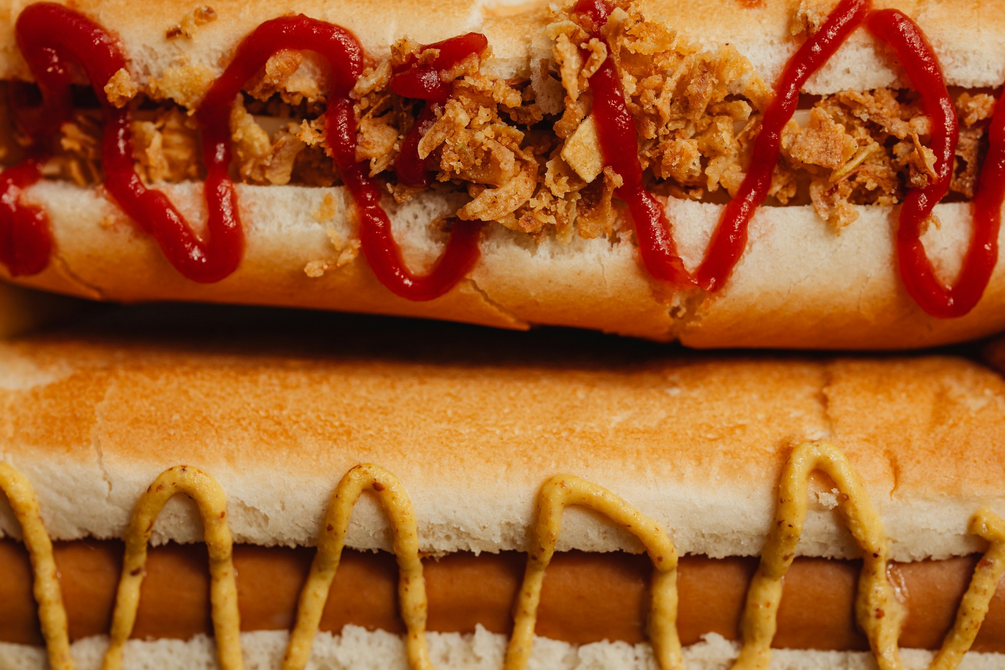 Two Icelandic hot dogs in buns topped with ketchup, garlic, and mustard.