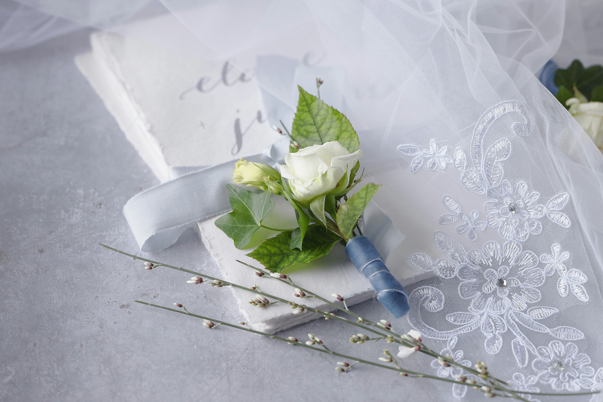 Simple wedding invitations with a flower resting on top.