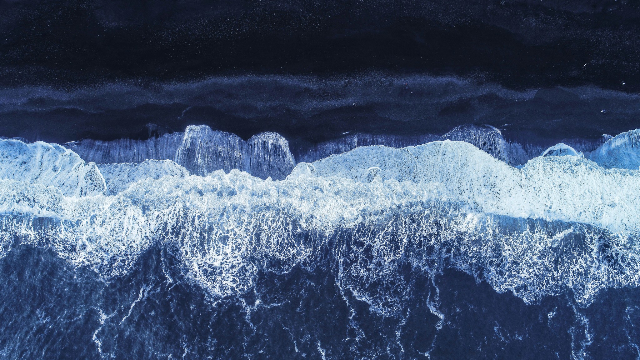 Powerful waves crashing onto a black sand beach in South Iceland.