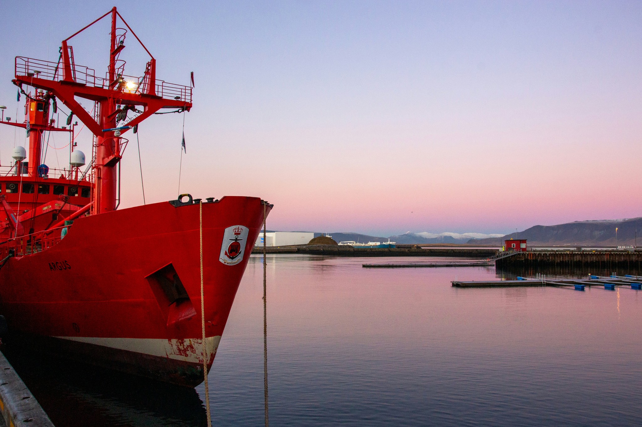 A large red boat moored in a harbor in Iceland.